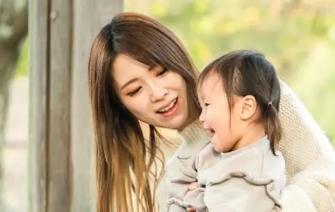 母親に2歳前後の娘が抱きしめられ、お互いに笑顔を浮かべている